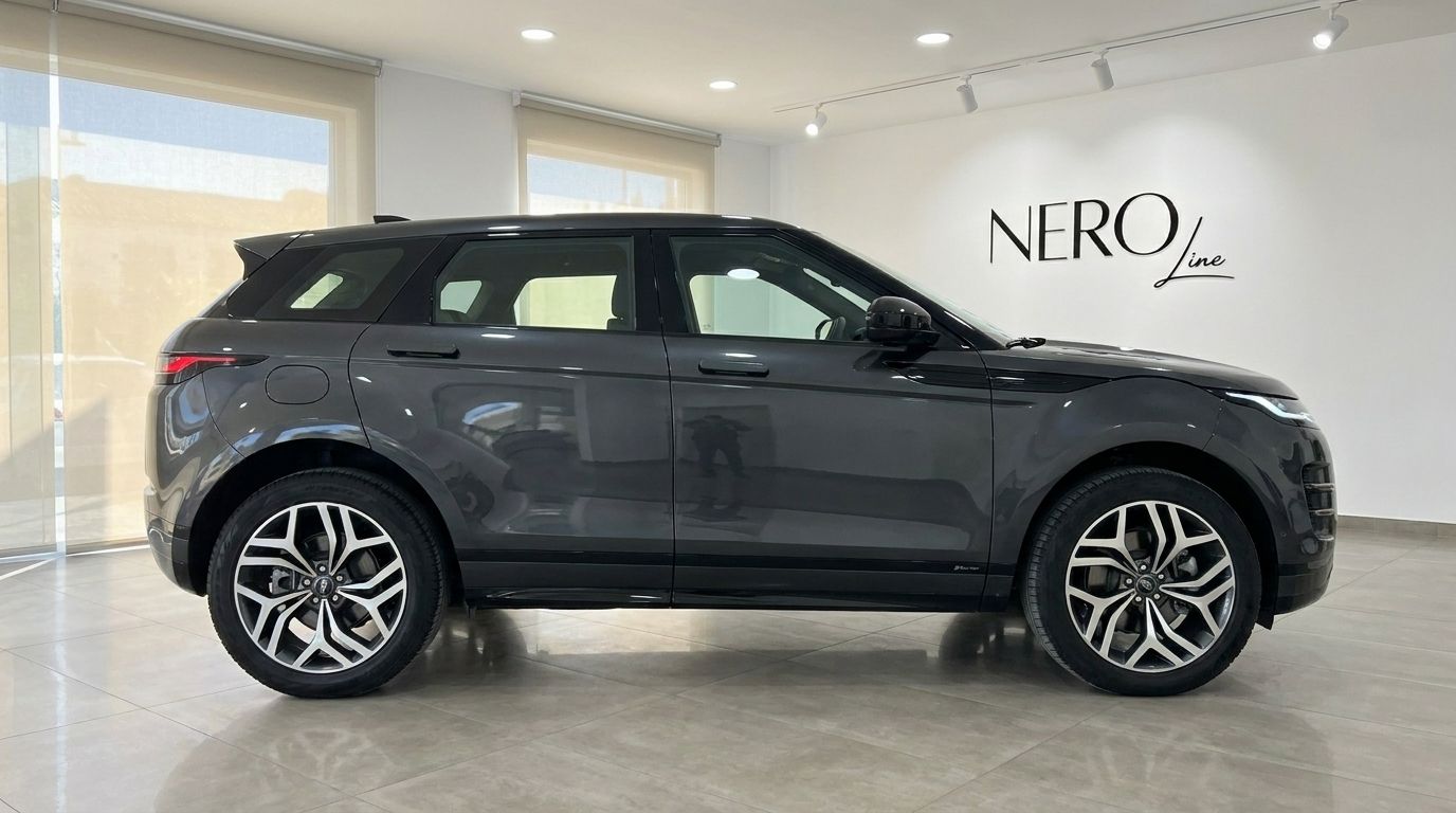 The dark grey Land Rover Range Rover Evoque R-Dynamic (1st) is showcased in a showroom, viewed from its side profile in Alicante.