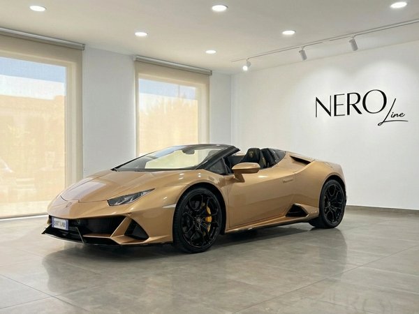 Lamborghini Huracan Evo Spyder — Ibiza showroom The golden beige 2024 Lamborghini Huracan Evo Spyder convertible is showcased from a front three-quarter view in a bright Ibiza showroom.