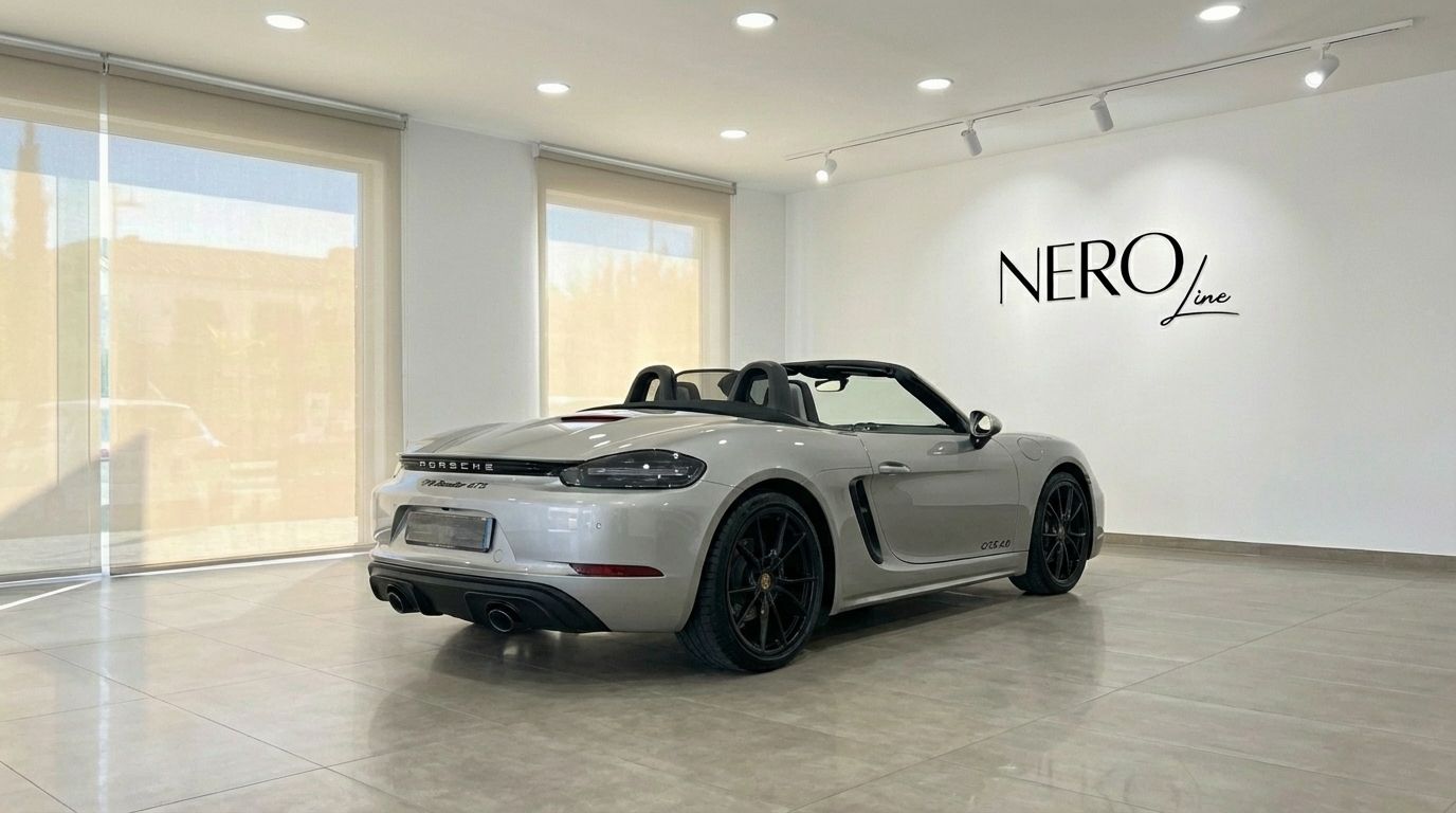 The metallic silver Porsche 718 Boxster 4.0 GTS convertible is parked in a Marbella showroom, viewed from the rear three-quarter angle.