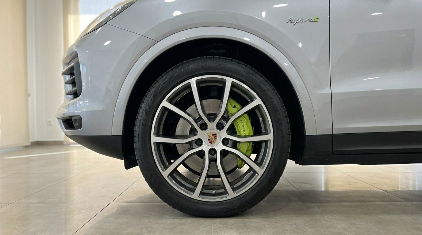 The front wheel of the silver metallic Porsche Cayenne Coupe in Marbella, showcasing its distinctive lime green brake calipers and alloy rim.
