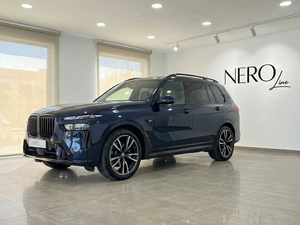 BMW X7 xDrive — Elegante SUV Azul Oscuro en Alicante El SUV de lujo BMW X7 xDrive 2023 azul oscuro está aparcado en una sala de exposición en Alicante, mostrando su elegante vista frontal tres cuartos.