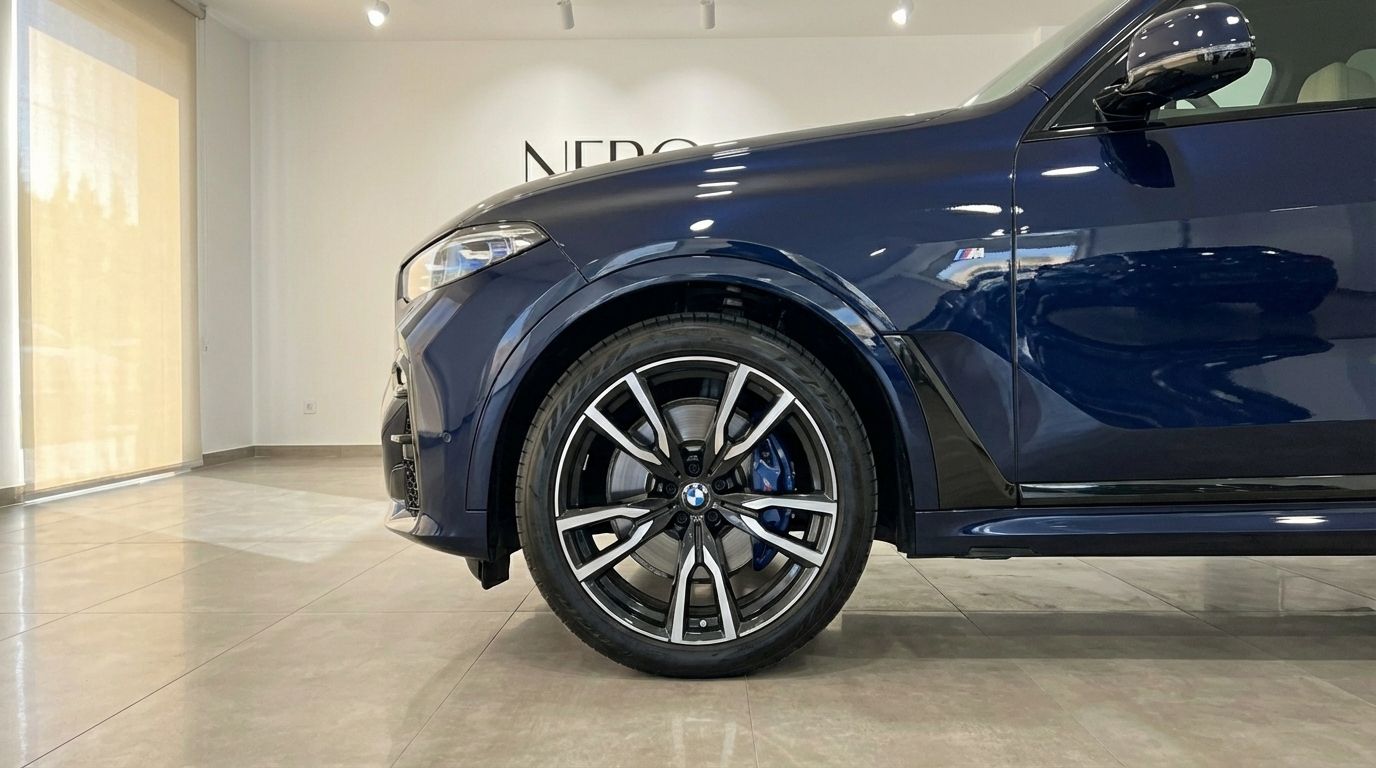 El BMW X7 xDrive azul oscuro muestra su intrincada rueda delantera con pinzas de freno azules y distintivo M en Alicante.