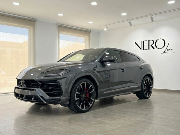 Lamborghini Urus S — Exposición en Madrid El Lamborghini Urus S 2024 gris grafito se exhibe en una vista frontal tres cuartos dentro de un lujoso showroom en Madrid.