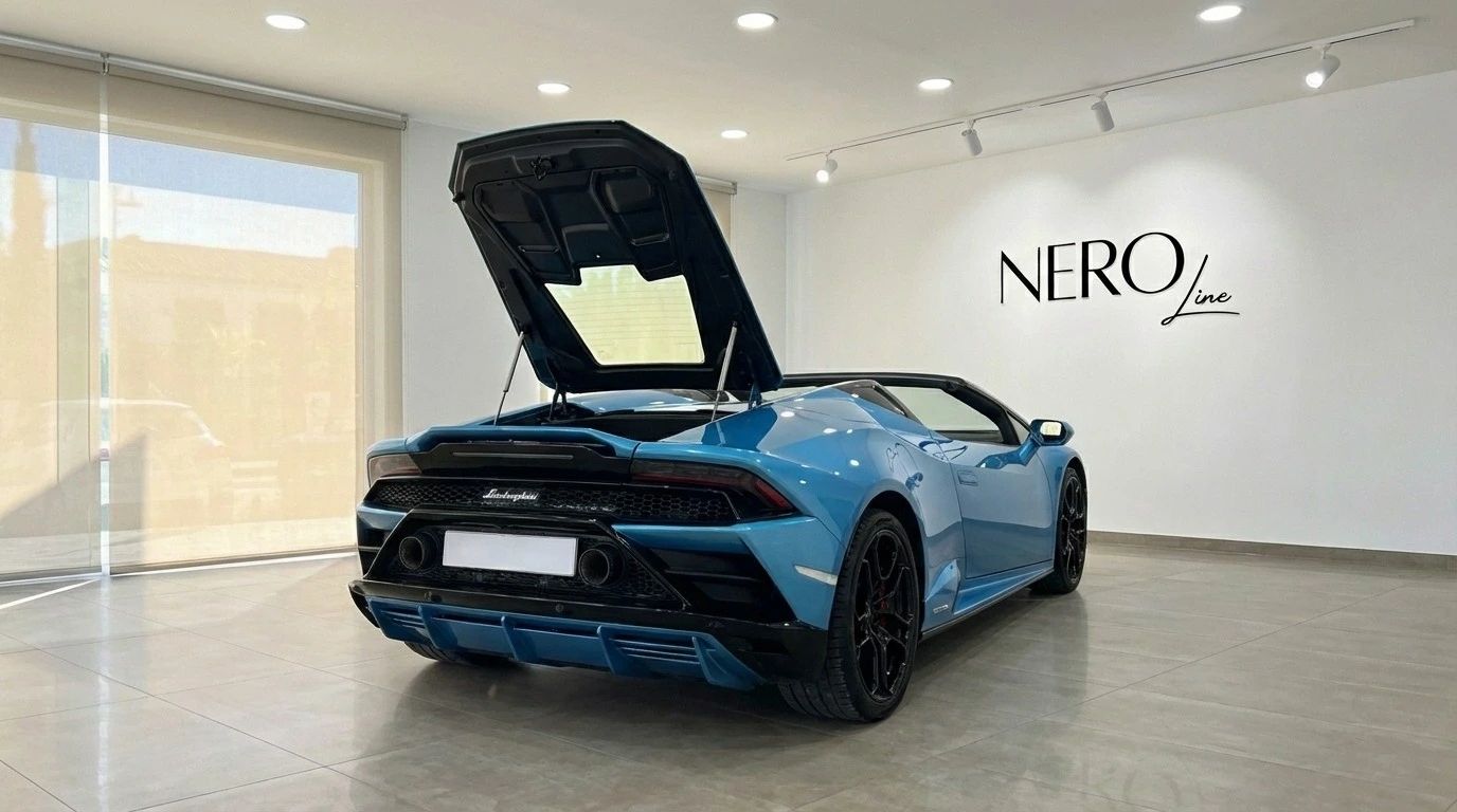 The metallic blue Lamborghini Huracan Evo Spyder from a rear-three-quarter view, with its engine cover open, in Marbella.