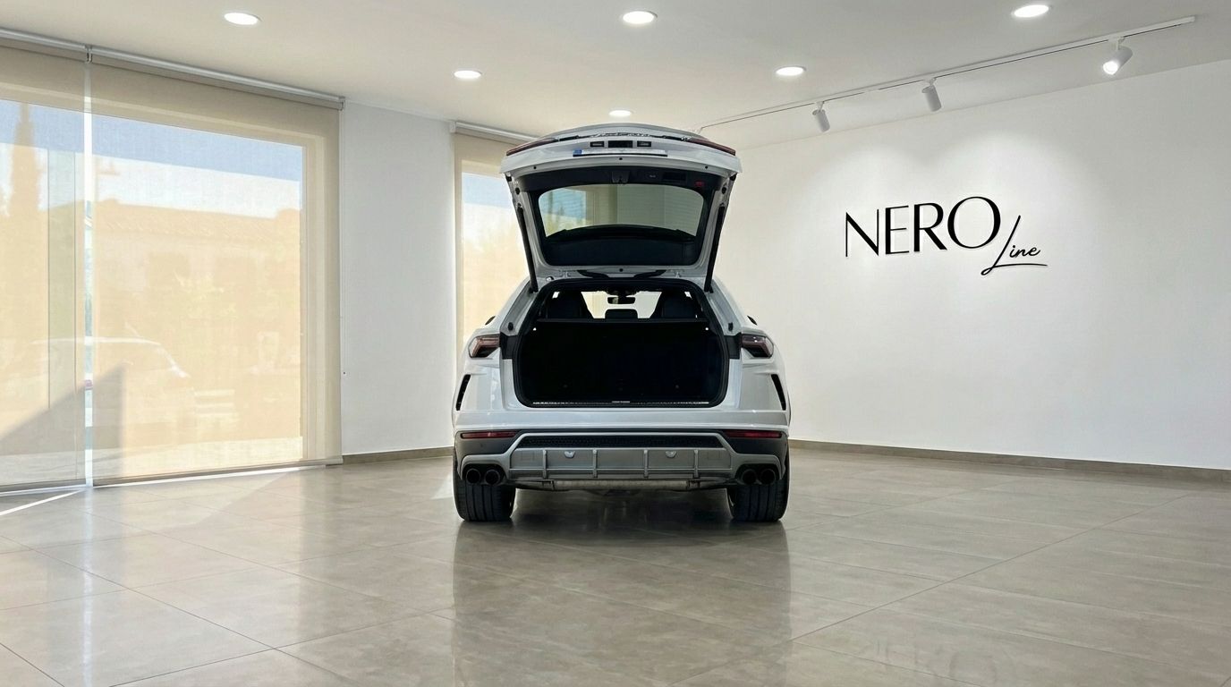 The pearl white Lamborghini Urus Super is shown from the rear with its trunk open, parked in a bright showroom in Alicante.