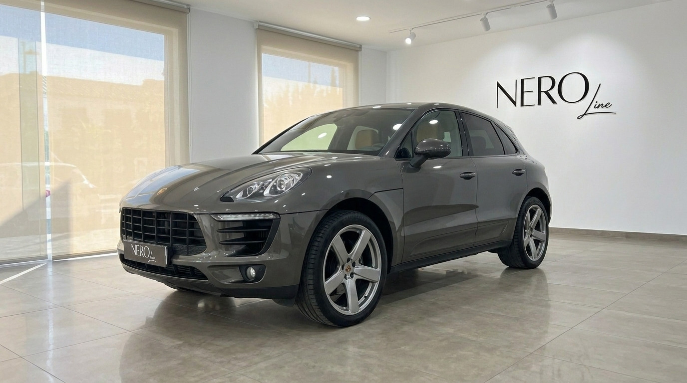 Porsche Macan 2.0 Turbo — Showroom in Alicante The gloss Volcano Grey Metallic Porsche Macan 2.0 Turbo is showcased from a front three-quarter angle inside a showroom in Alicante.