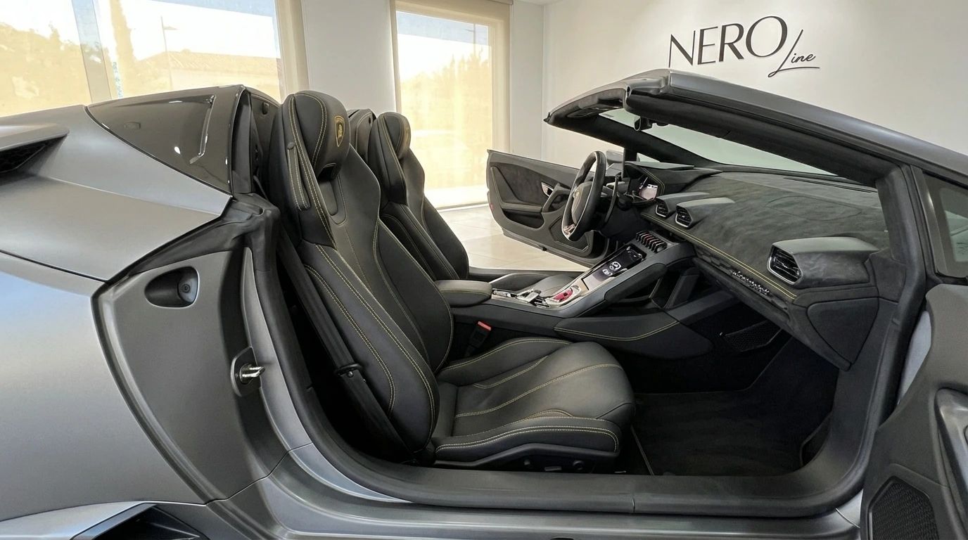 The Lamborghini Huracan Evo Spyder interior in matte gray features black leather seats with yellow stitching and a detailed dashboard, visible in Ibiza.