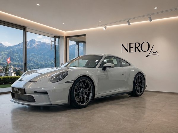 Porsche GT3 RS — Luxury showroom in Zurich The Porsche GT3 RS in gloss Arctic Grey is showcased indoors, with a panoramic view of the Zurich mountains.