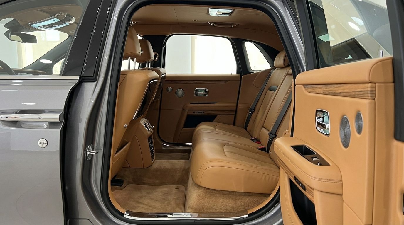L'intérieur arrière luxueux de la Rolls-Royce Ghost à Madrid, présentant ses sièges en cuir fauve exquis et ses boiseries élégantes avec la porte ouverte.