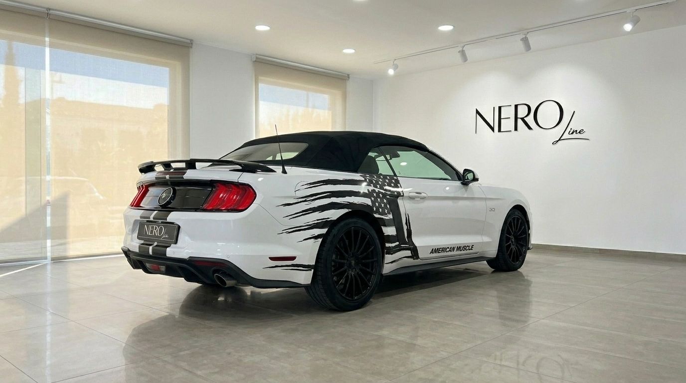 The white Ford Mustang 2.3 Convertible with a black American flag graphic is parked in a showroom in Benidorm.