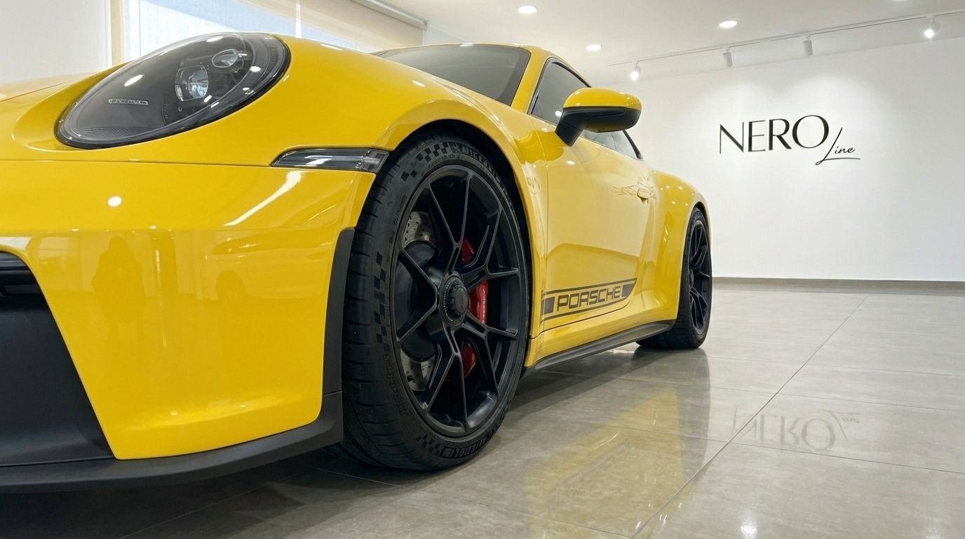 Una vista ad angolo basso del lato anteriore sinistro della Porsche 911 GT3 992 gialla, evidenziando faro e ruota nera ad Alicante.