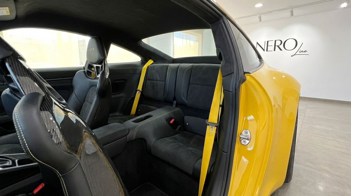 L'interno della Porsche 911 GT3 992 gialla ad Alicante, con sedili a guscio in fibra di carbonio neri e cinture di sicurezza gialle abbinate.