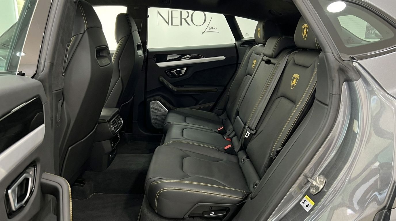 The luxurious rear interior of the Lamborghini Urus Full Black in Marbella, featuring black leather seats with yellow stitching and embossed logos.