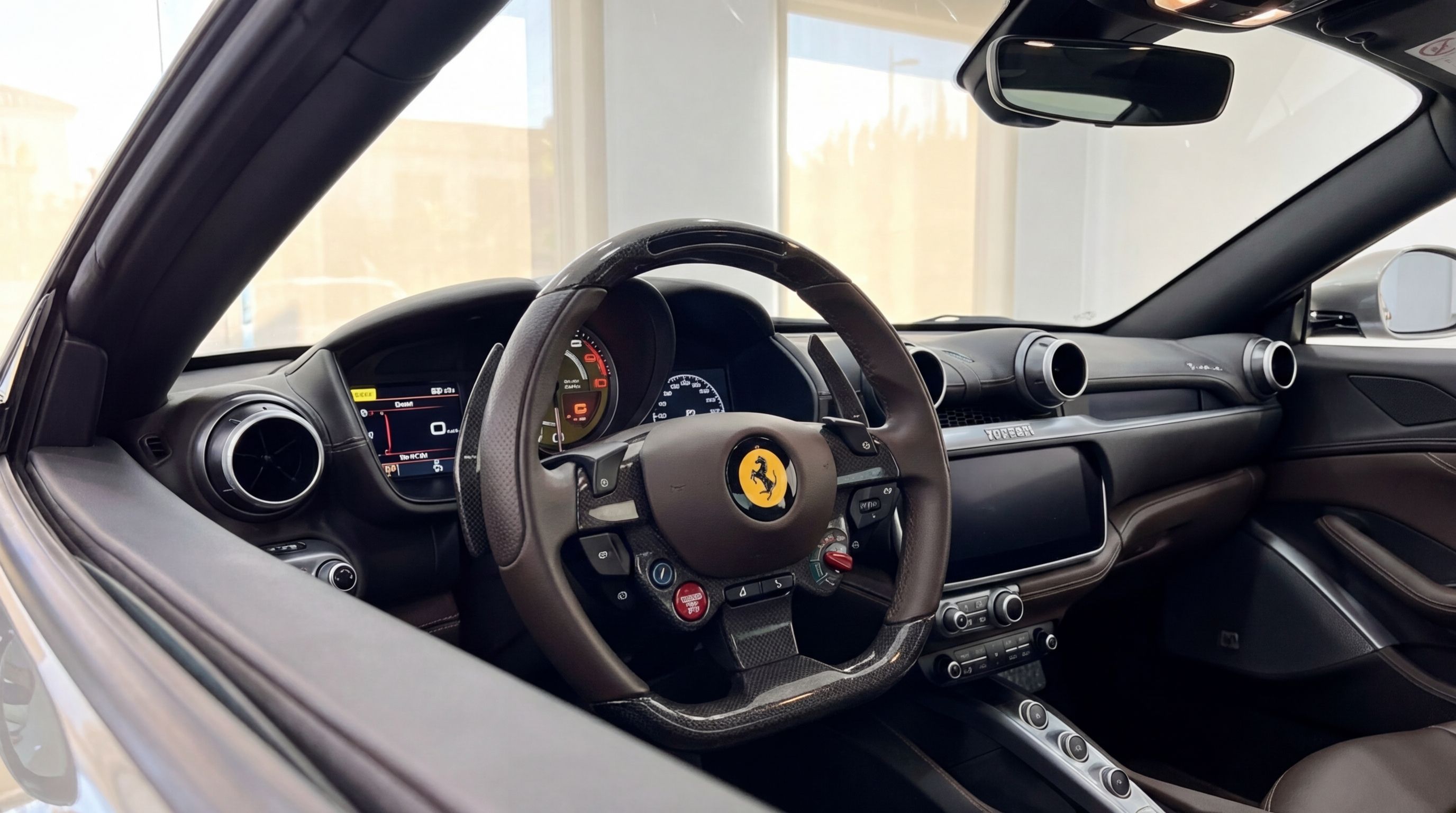 The luxurious interior of the Ferrari Portofino in Malaga, showcasing the brown leather steering wheel, digital dashboard, and central console.