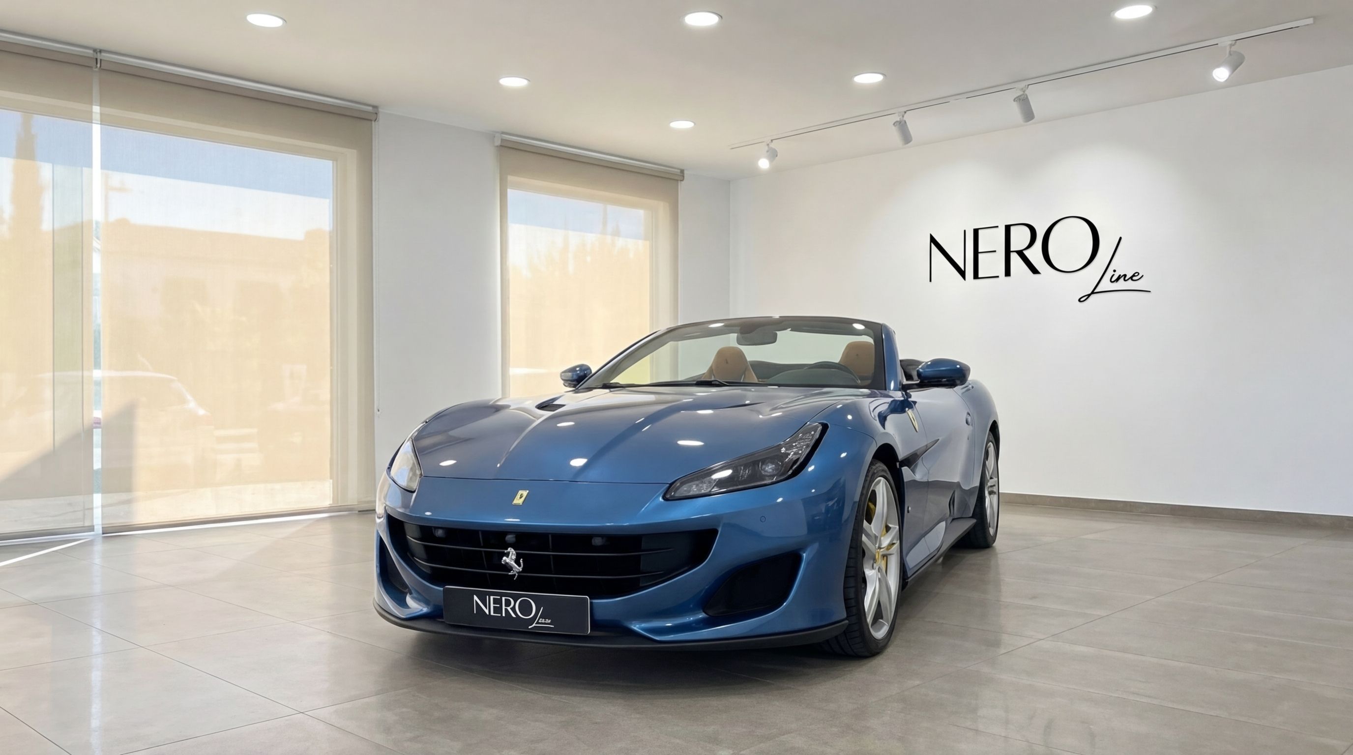 The metallic blue Ferrari Portofino convertible is presented from a front three-quarter angle in a bright Malaga showroom.