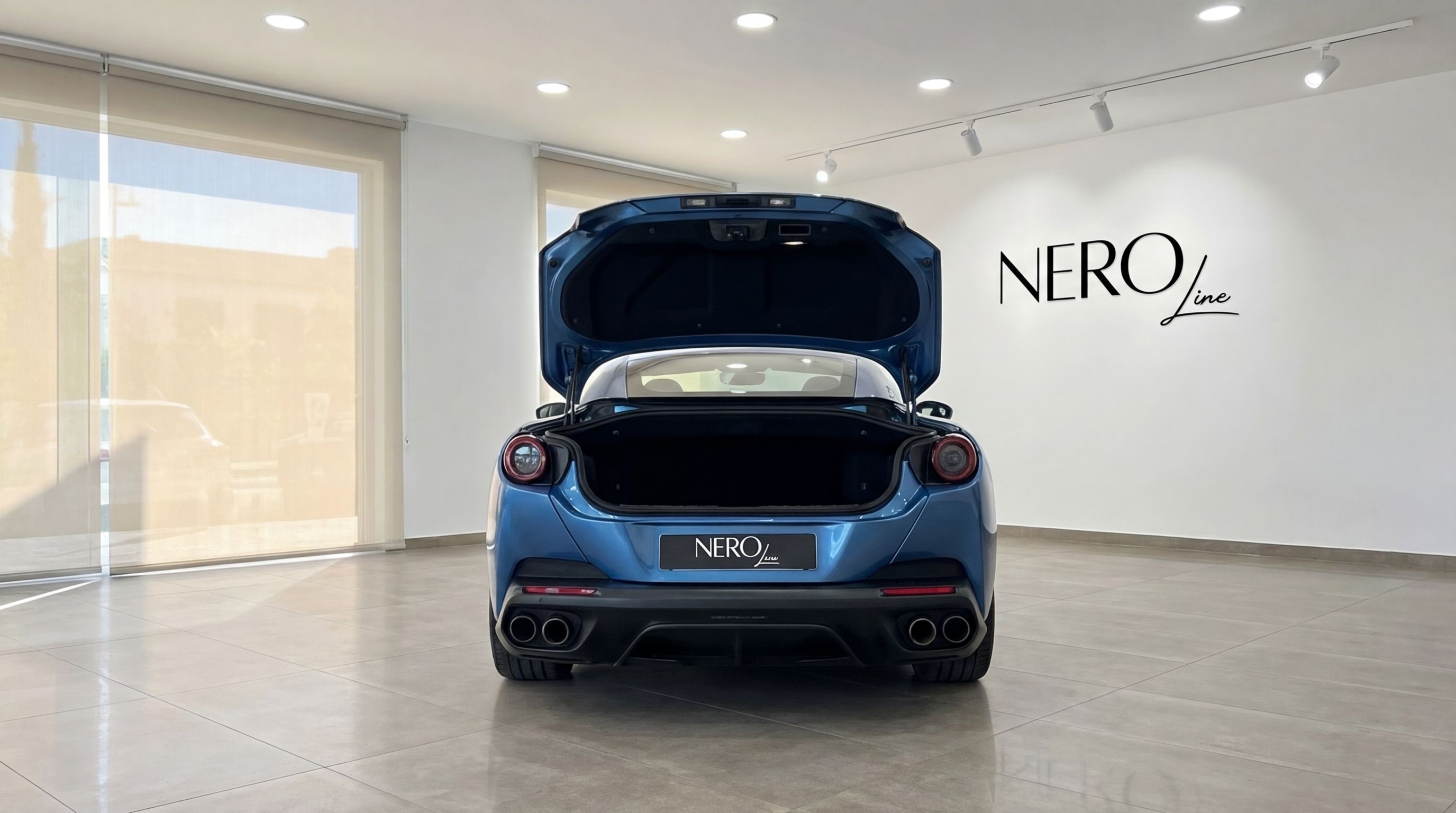 Metallic blue Ferrari Portofino from the rear, with its trunk open, displayed in a bright showroom in Malaga.