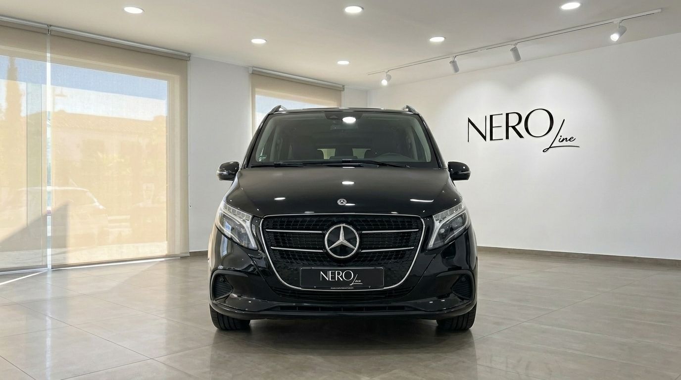 A black Mercedes-Benz V-Class is shown head-on in a bright showroom in Marbella, featuring its prominent grille and headlights.