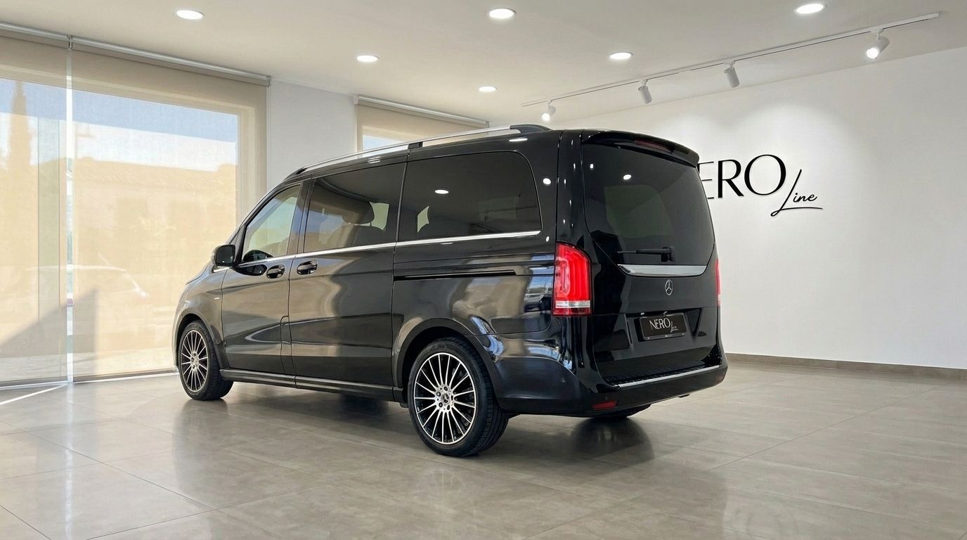The gloss Obsidian Black Mercedes-Benz V250d Hermes VIP is shown from a rear three-quarter angle in a Barcelona showroom.