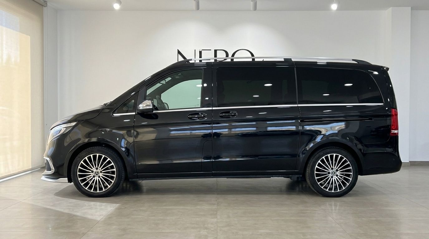 The gloss Obsidian Black Mercedes-Benz V250d Hermes VIP is parked in a showroom, showcasing its elegant side profile in Barcelona.