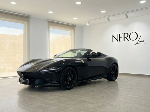 Ferrari Roma Spider Black — Showroom view Madrid The 2025 Ferrari Roma Spider Black, with its top down and red interior, is showcased in a showroom in Madrid.