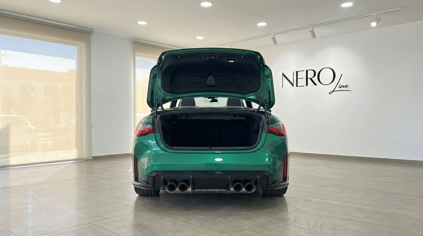 The emerald green BMW M4 Competition Convertible is shown from the rear with its trunk open in a showroom in Alicante.