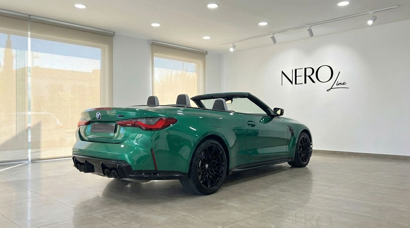 The emerald green BMW M4 Competition Convertible is showcased from a rear three-quarter angle with its top down in a showroom in Alicante.