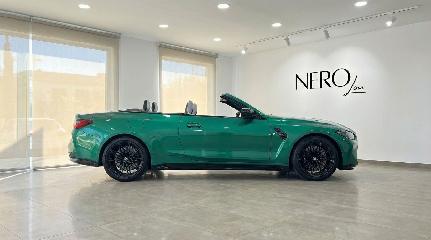 The emerald green 2025 BMW M4 Competition Convertible is shown in a side profile view with its top down, parked in a showroom in Alicante.