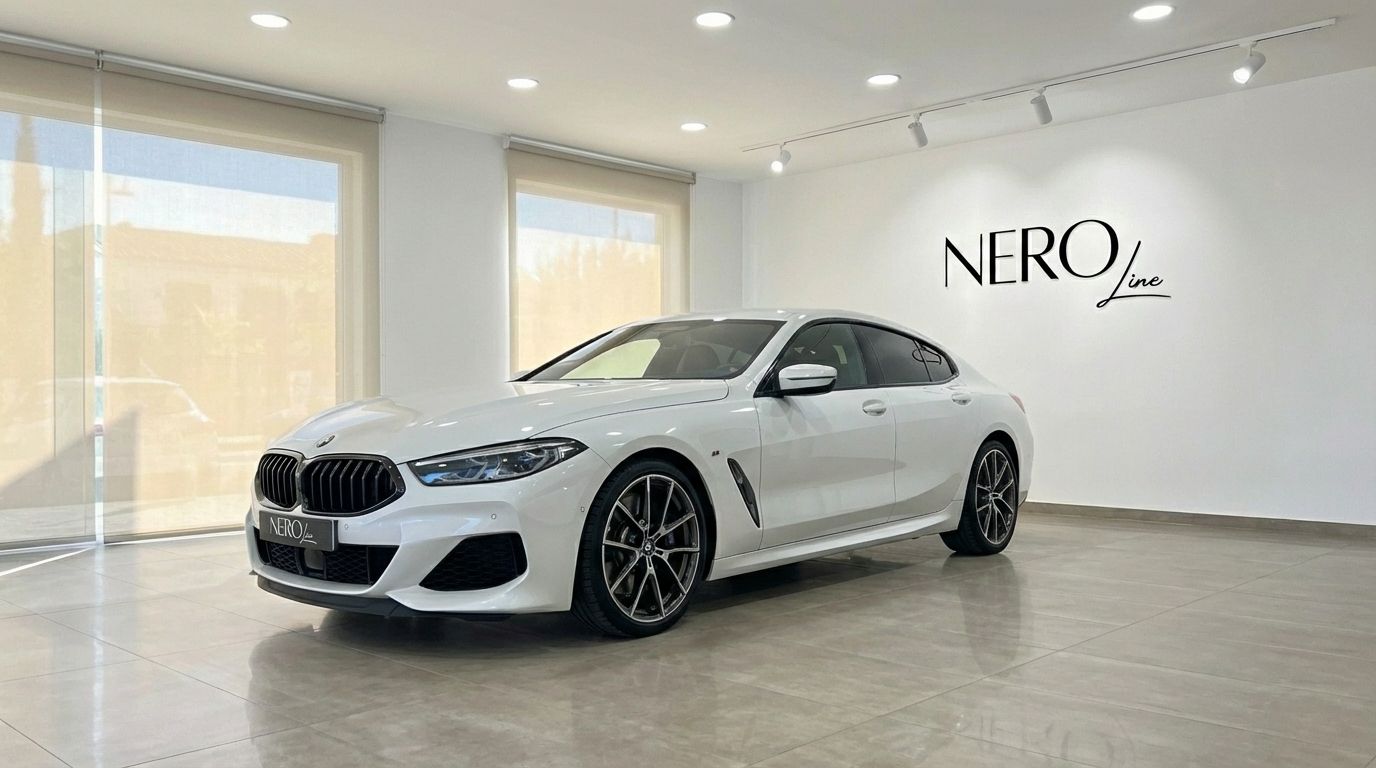The white 2022 BMW M850i Grandcoupe is showcased from a front three-quarter angle inside the NEROline showroom in Barcelona.