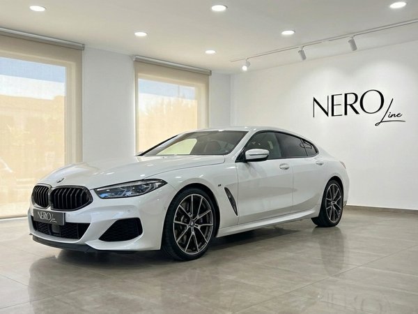 BMW M850i Grandcoupe — Luxury rental in Barcelona The white 2022 BMW M850i Grandcoupe is showcased from a front three-quarter angle inside the NEROline showroom in Barcelona.