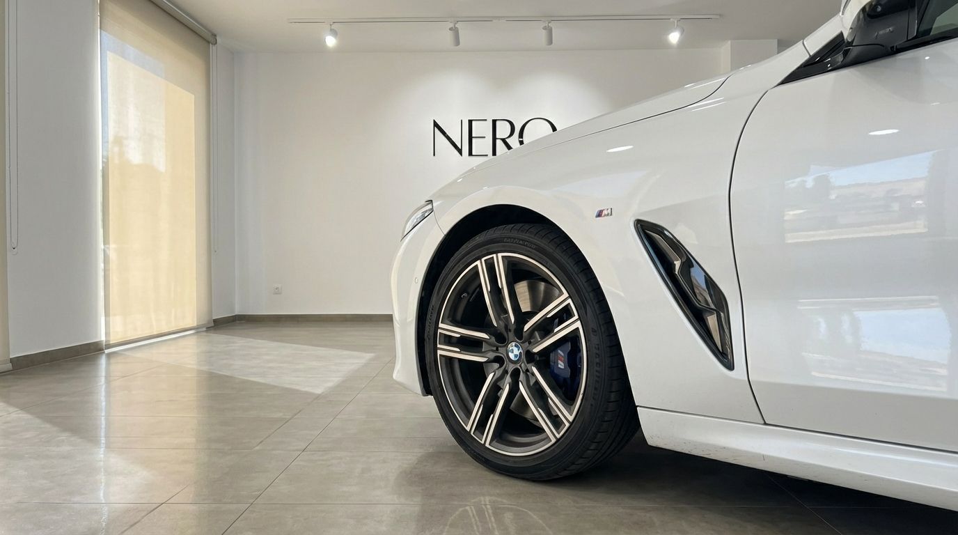 The white BMW M850i Grandcoupe's front wheel and side panel are prominently displayed, with the NERO logo visible in the background in Barcelona.