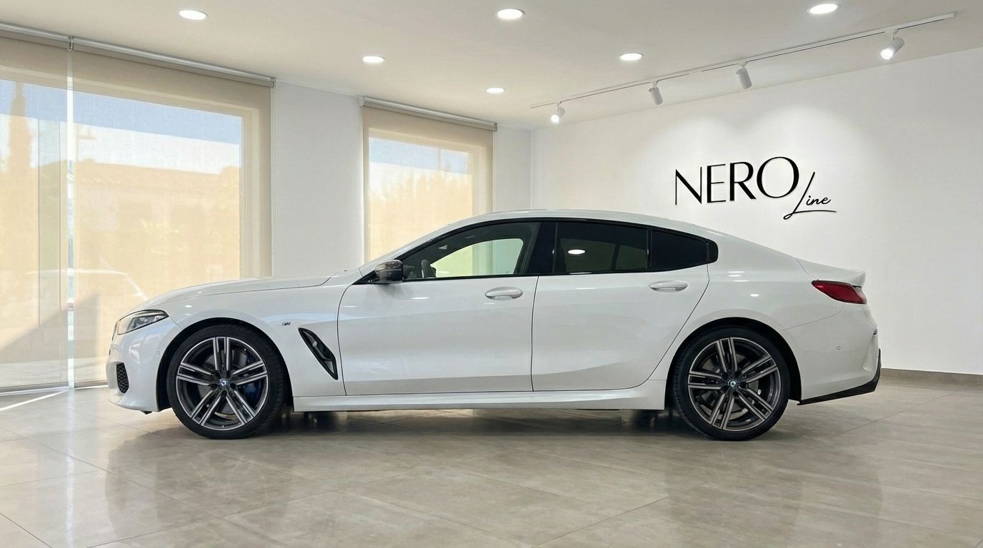 The white BMW M850i Grandcoupe is showcased from its side profile in a bright Barcelona showroom.