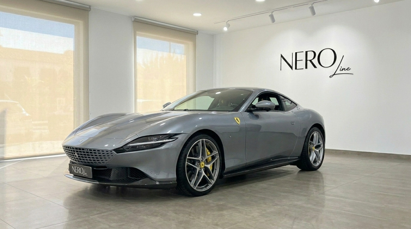 Ferrari Roma — Vista frontal tres cuartos, Madrid El Ferrari Roma 2022 gris metálico se exhibe desde un ángulo frontal tres cuartos en un luminoso showroom en Madrid.