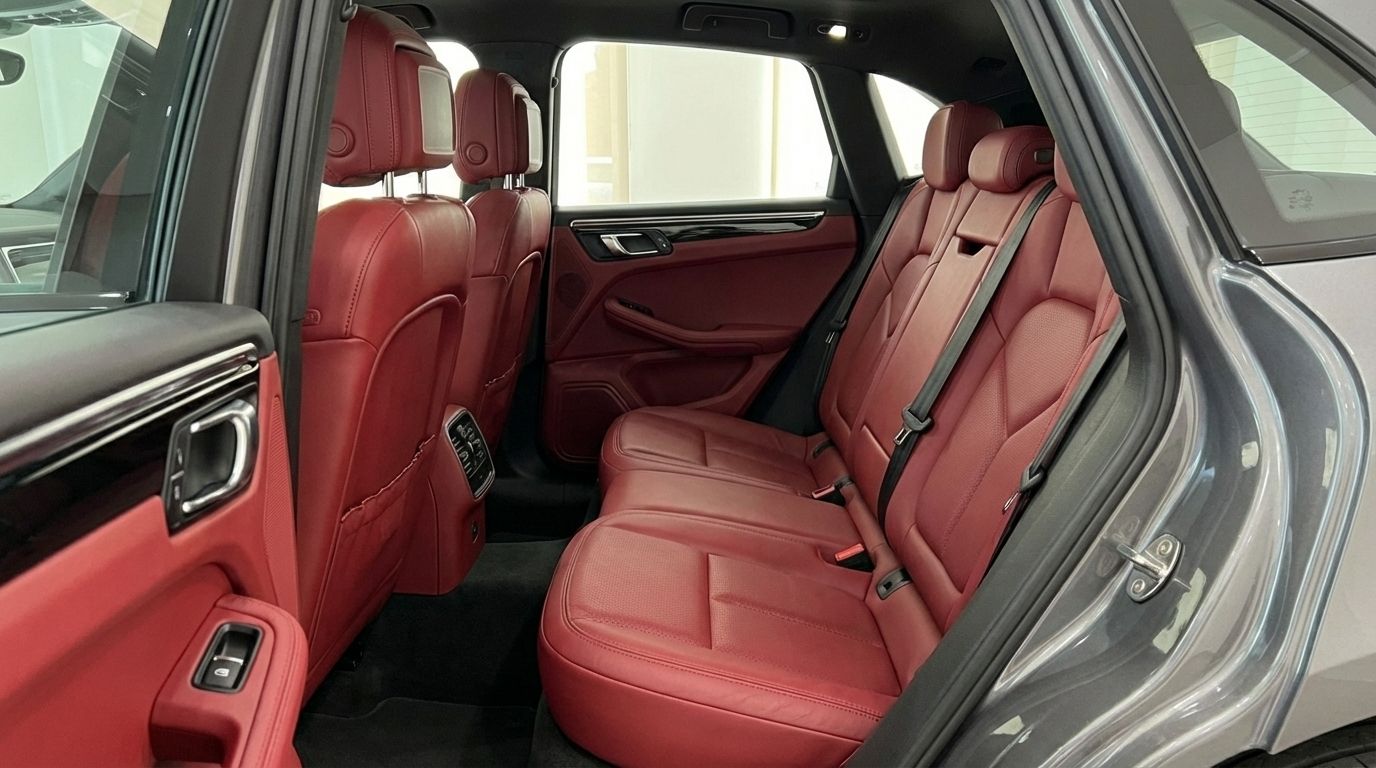 The luxurious red leather rear seats and door panel of the 2021 Porsche Macan S, available for rent in Alicante.