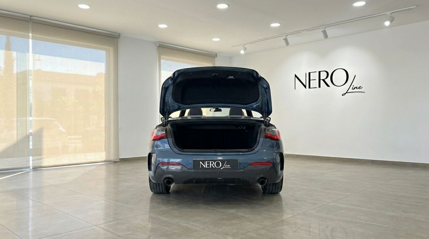 The BMW 420 Cabriolet is seen from the rear with its trunk open, showcasing its design inside a showroom in Alicante.