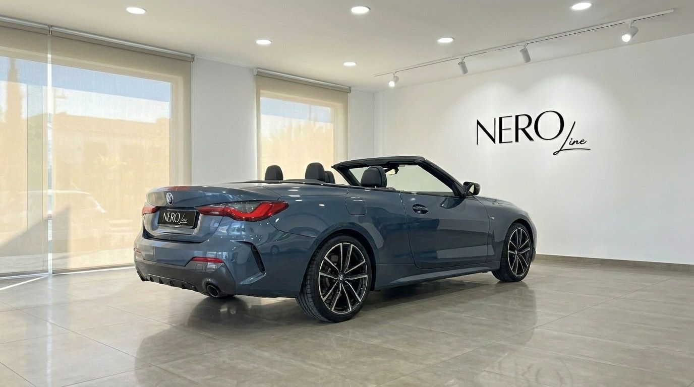The grey-blue BMW 420 Cabriolet is shown from a rear three-quarter angle with its top down, parked indoors in Alicante.