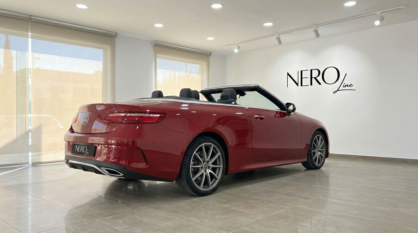 A red Mercedes-Benz E300 Cabrio is parked indoors, viewed from the rear three-quarter with its top down in Alicante.