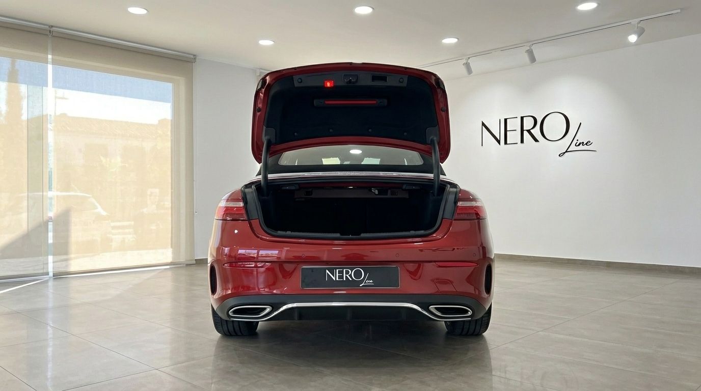 Rear view of a red Mercedes-Benz E300 Cabrio with its trunk open, displayed in a showroom in Alicante.