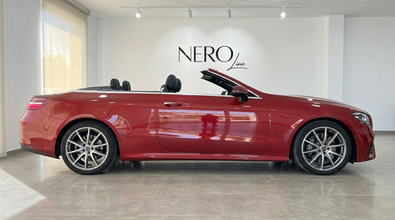 The red Mercedes-Benz E300 Cabrio, with its convertible top down, is showcased from a side view in a bright Alicante showroom.
