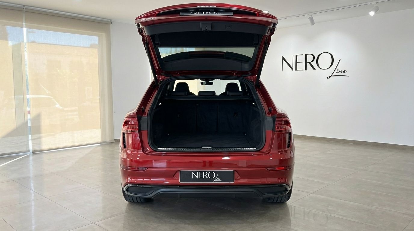Metallic red Audi SQ8 with its trunk open, showcasing the spacious cargo area in Alicante.