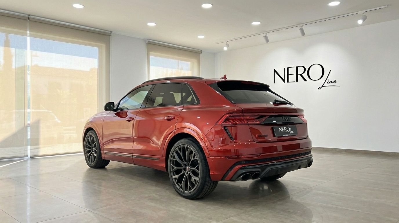 The metallic red Audi SQ8 with RSQ8 body kit is shown from a rear three-quarter angle in a showroom in Alicante.
