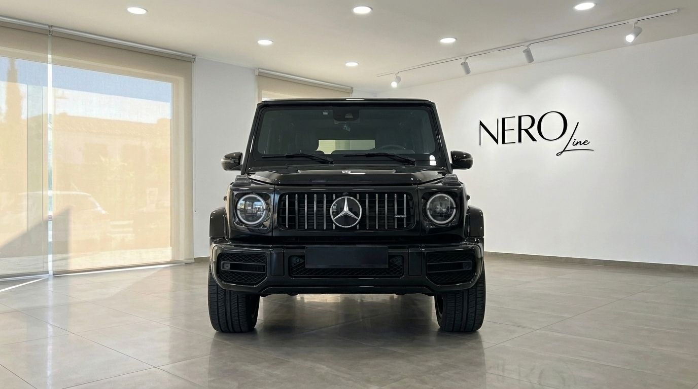 The glossy black Mercedes-Benz AMG G 63 is prominently displayed from the front in a modern showroom in Alicante.