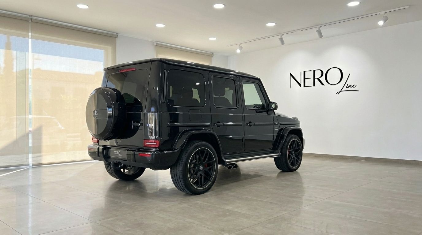 The glossy black Mercedes-Benz AMG G 63 is parked indoors, showcasing its powerful rear three-quarter view in Alicante.