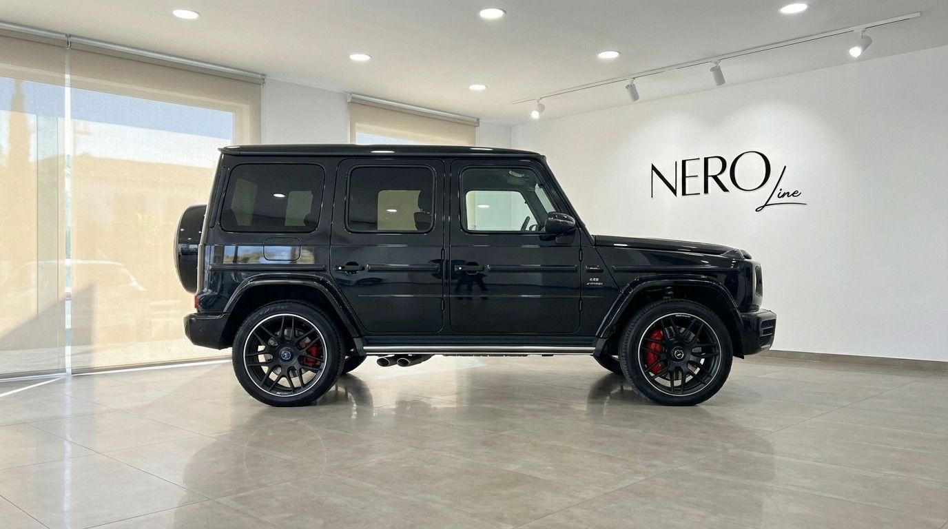 A glossy black Mercedes-Benz AMG G 63 SUV is shown from its side profile, parked in a modern showroom in Alicante.