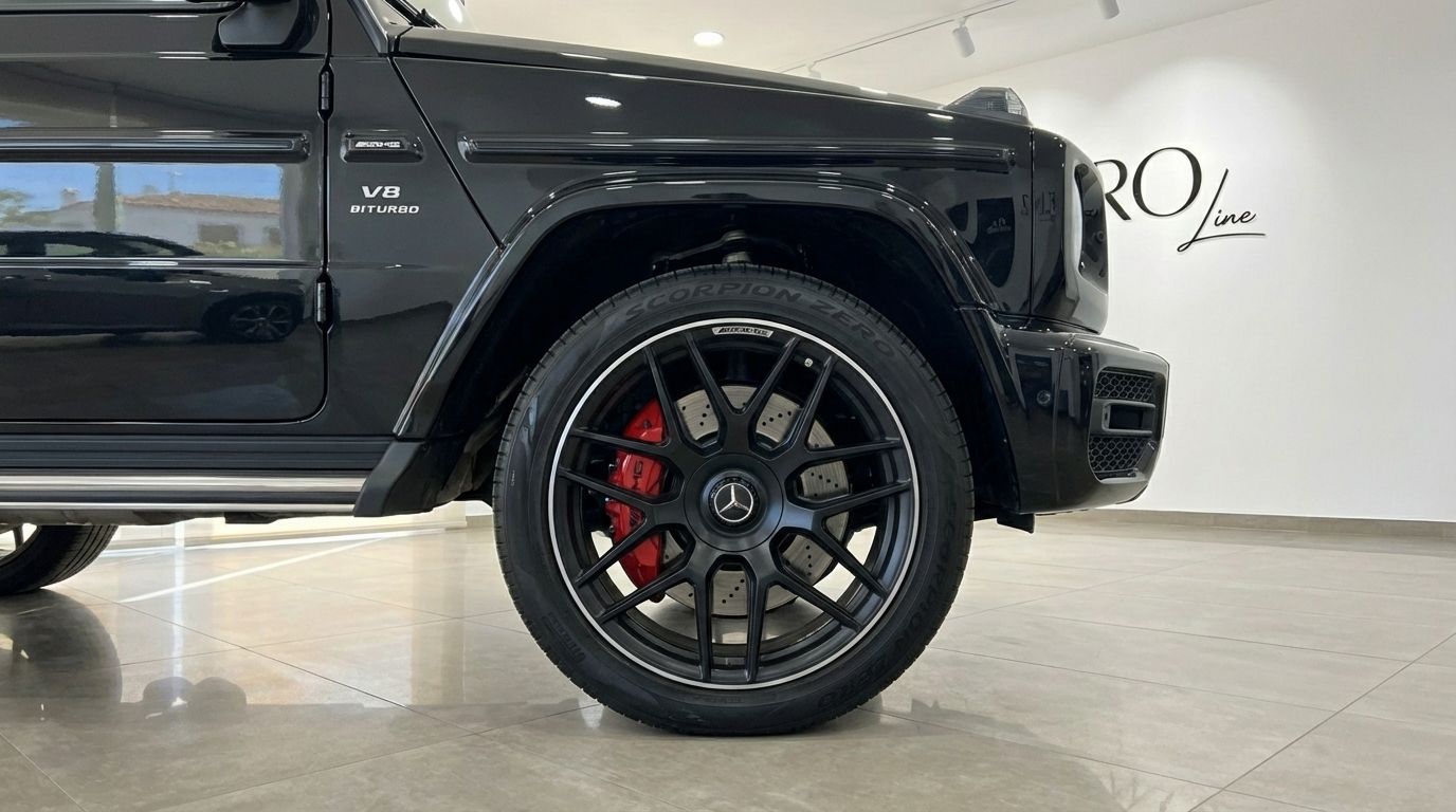 The glossy black Mercedes-Benz AMG G 63, showcasing its front wheel with red brake calipers, parked in Alicante.