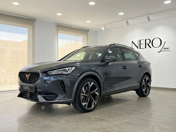 Cupra Terramar — Vue trois quarts avant en showroom Un SUV Cupra Terramar gris foncé métallisé brillant est présenté de trois quarts avant dans un showroom lumineux à Alicante.