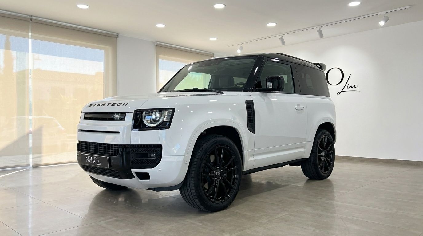 The white Land Rover Defender 90 Startech Edition is showcased from a front three-quarter angle indoors in Marbella.