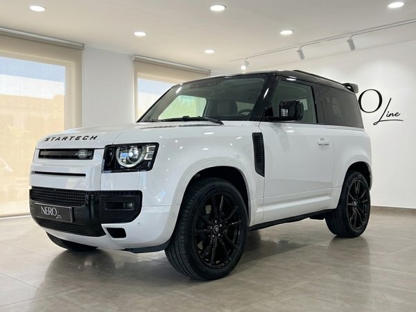 Land Rover Defender 90 Startech — Marbella Showroom The white Land Rover Defender 90 Startech Edition is showcased from a front three-quarter angle indoors in Marbella.