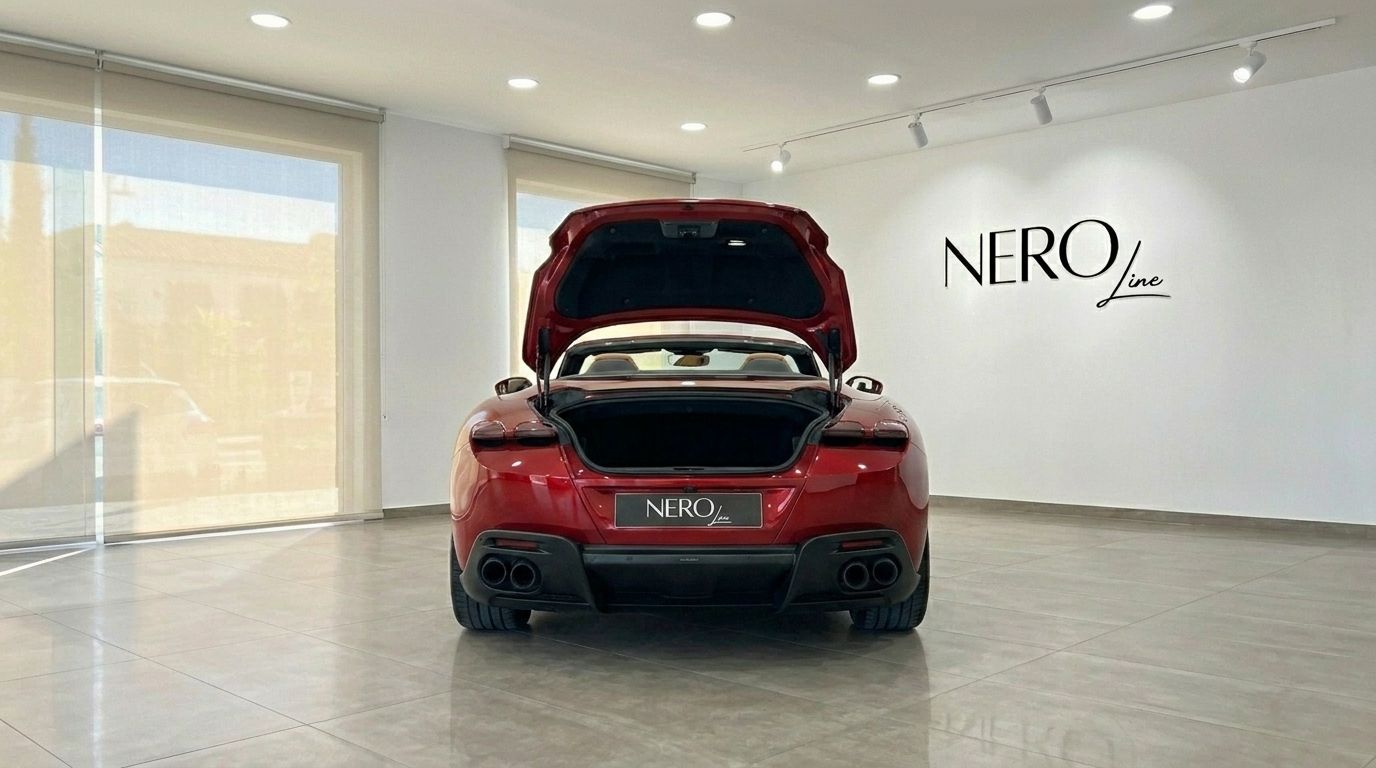 Rear view of the racing red 2023 Ferrari Roma Spider with its trunk and convertible top compartment open in a Barcelona showroom.