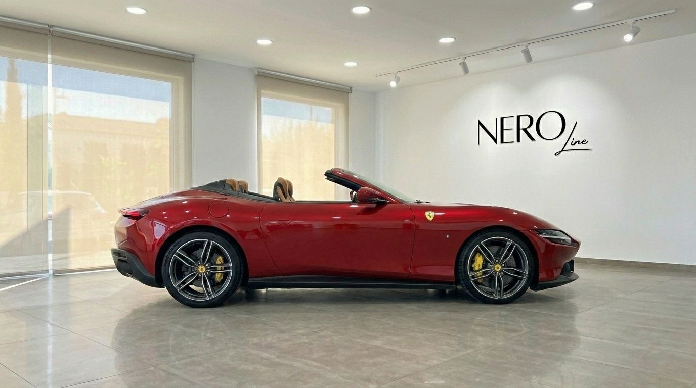 The red Ferrari Roma Spider convertible is parked with its top down, displaying its elegant side profile in a Barcelona showroom.