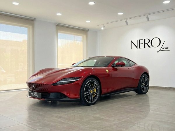 Ferrari Roma — Front three-quarter view, Barcelona The racing red 2023 Ferrari Roma is showcased from a front three-quarter view inside a showroom in Barcelona.
